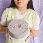 Chica cogiendo una tarta con "GEN Z" en ella